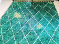 Green wool rug with large bleach spots demonstrating fibers suitable for carpet dyeing